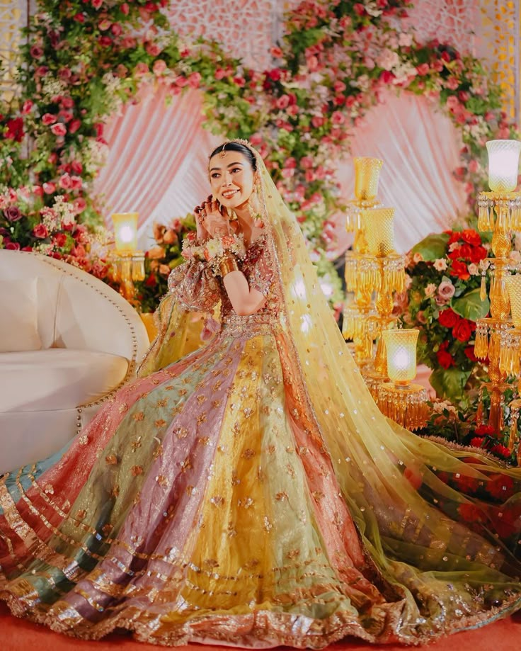 a woman in a colorful wedding dress standing next to a white couch and chandelier