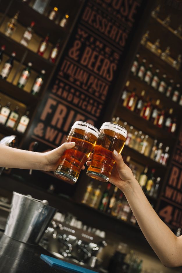 two women are toasting with beer at the bar