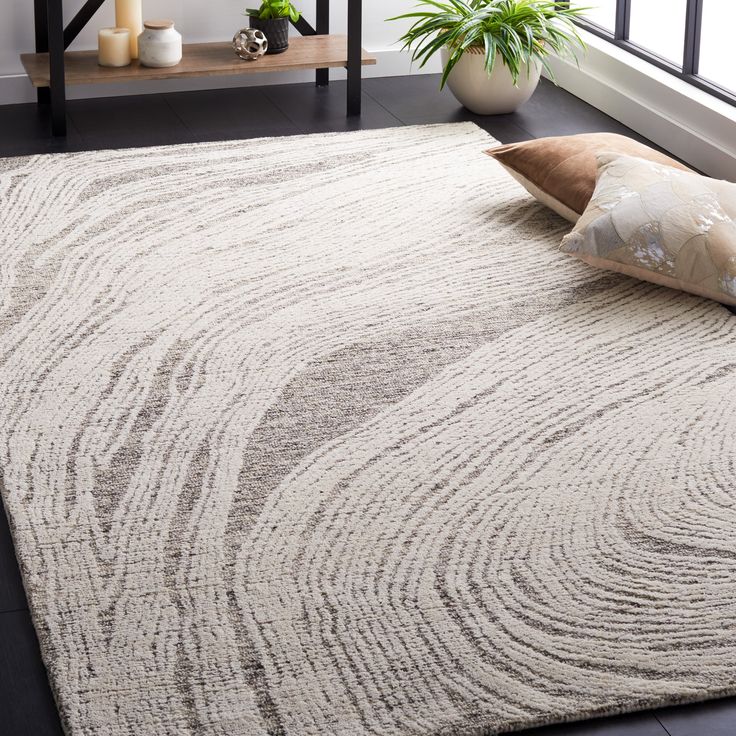 a white rug with wavy lines on it in front of a window and potted plant