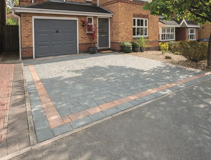 a brick driveway in front of a house with two garage doors on each side and one car door open