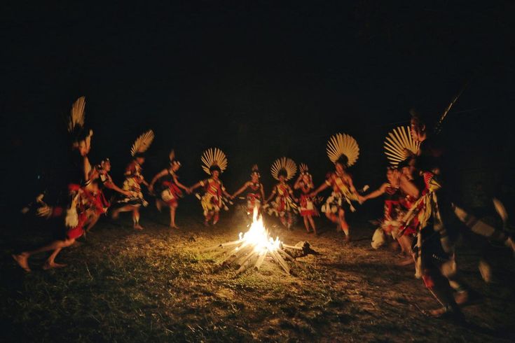 a group of people dancing around a fire