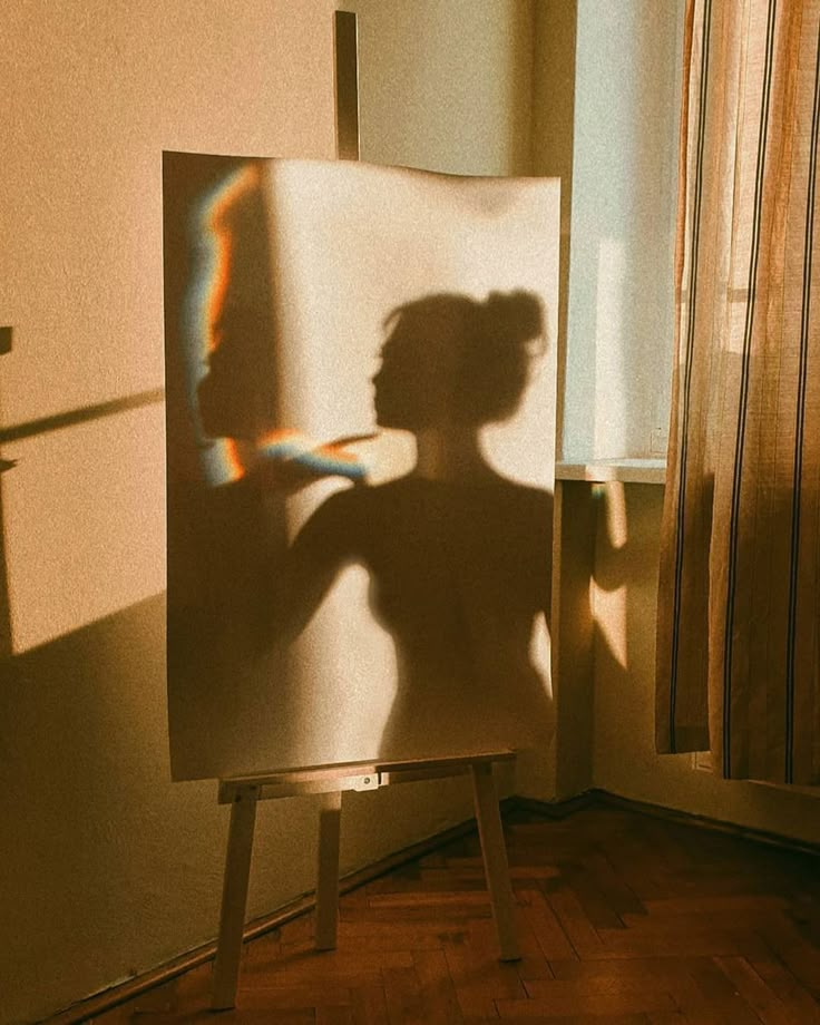 the shadow of a woman's head is shown on an easel