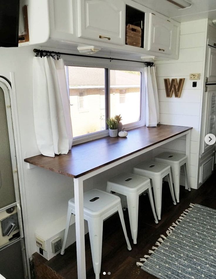 the inside of a mobile home with white stools and a table in front of it