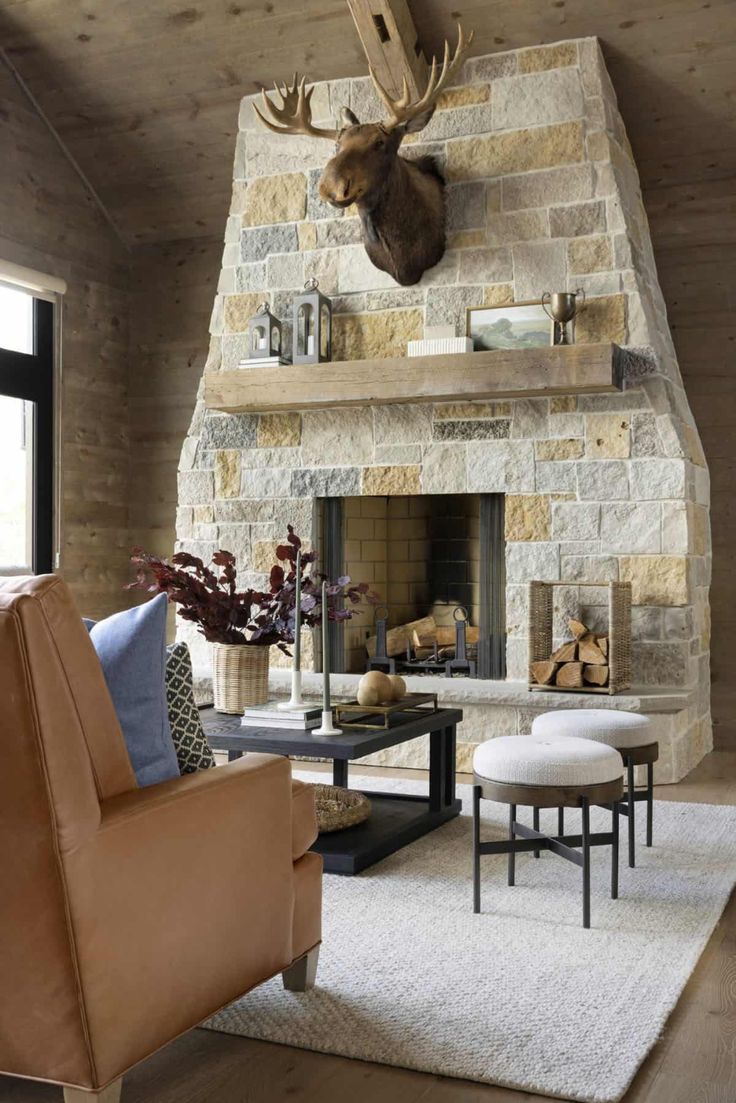 a living room with a stone fireplace and deer head mounted on the wall above it