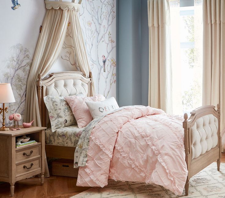 a bed with pink comforter and pillows on top of it next to a window