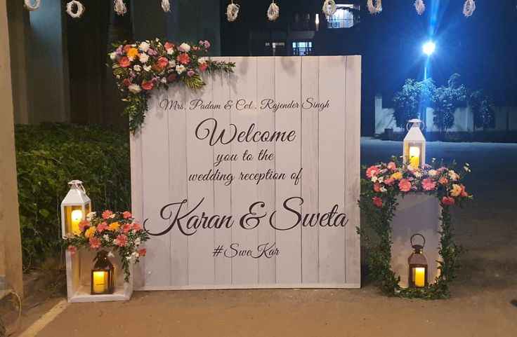 a welcome sign with lanterns and flowers on it