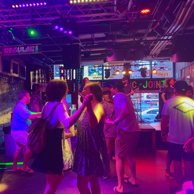 a group of people standing around in a room with neon lights on the walls and floor