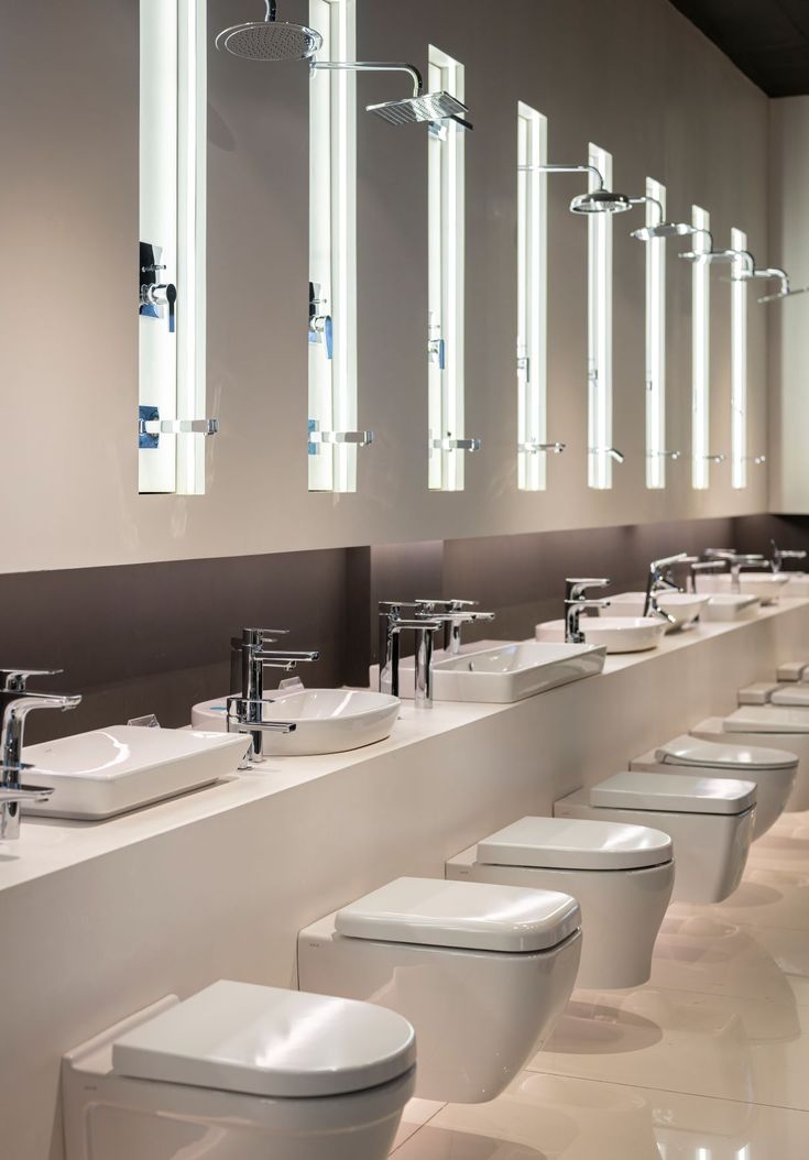 a long row of sinks and toilets in a bathroom with mirrors on the wall above them