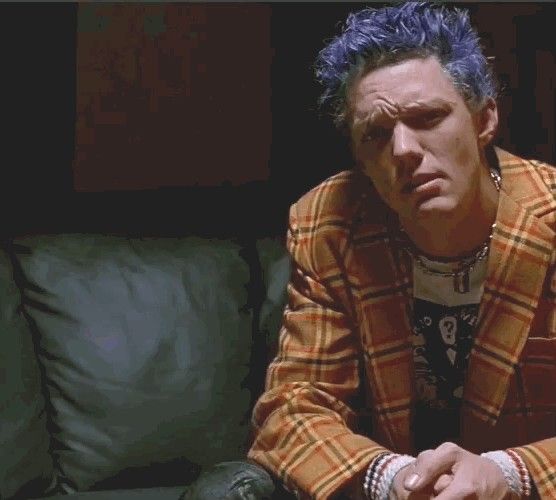 a man with blue hair sitting on a couch