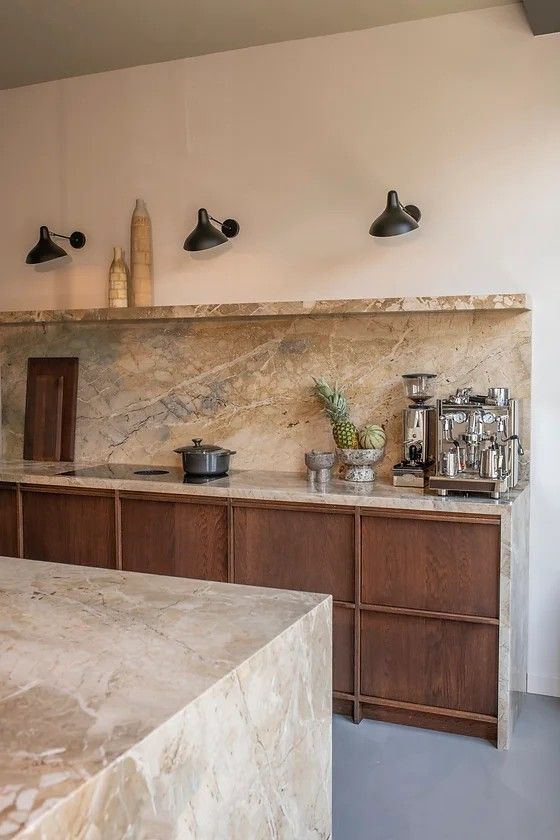 a kitchen with marble counter tops and wooden cabinets, along with potted plants on the wall