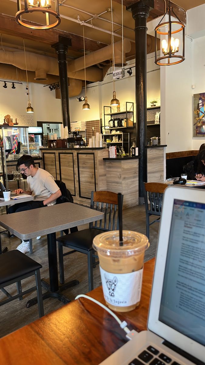 a laptop computer sitting on top of a wooden table next to a cup of coffee