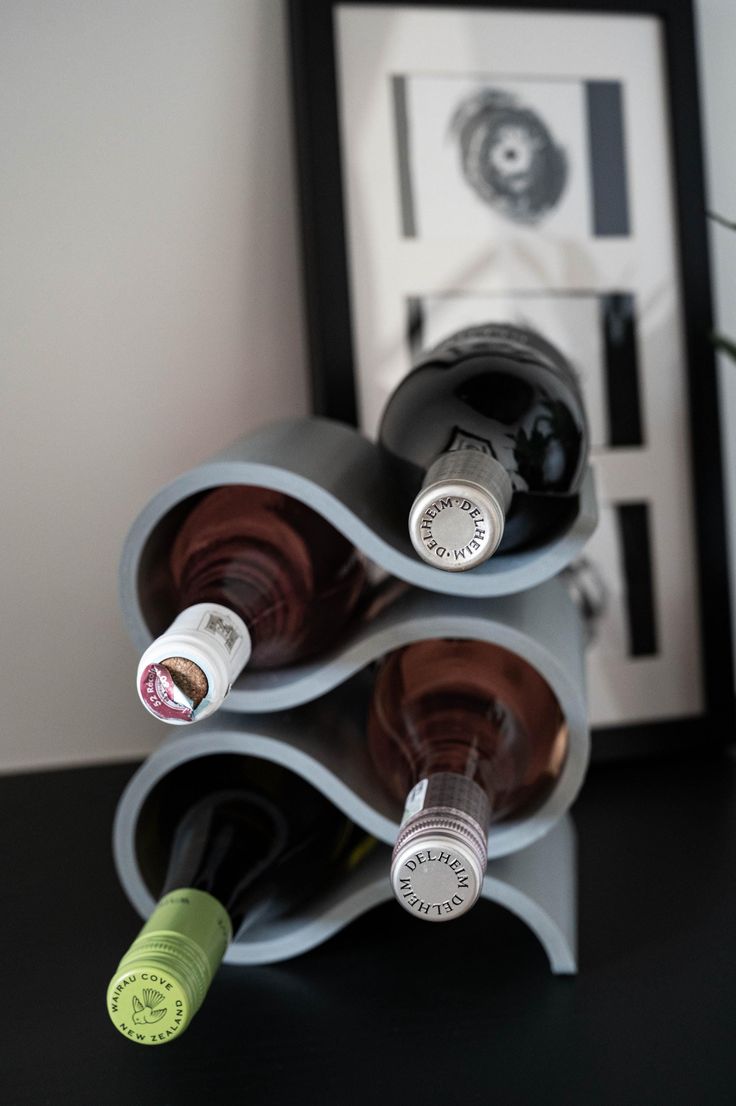 three bottles of wine are stacked up on a shelf in front of a framed photograph