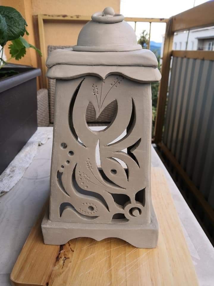 a cement lantern sitting on top of a wooden table next to a potted plant