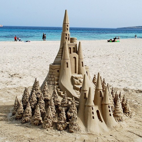 a sand castle on the beach with people in the background