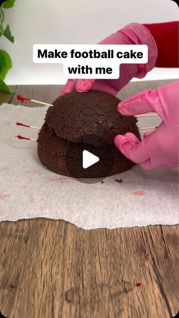 a person in pink gloves is decorating a chocolate cake