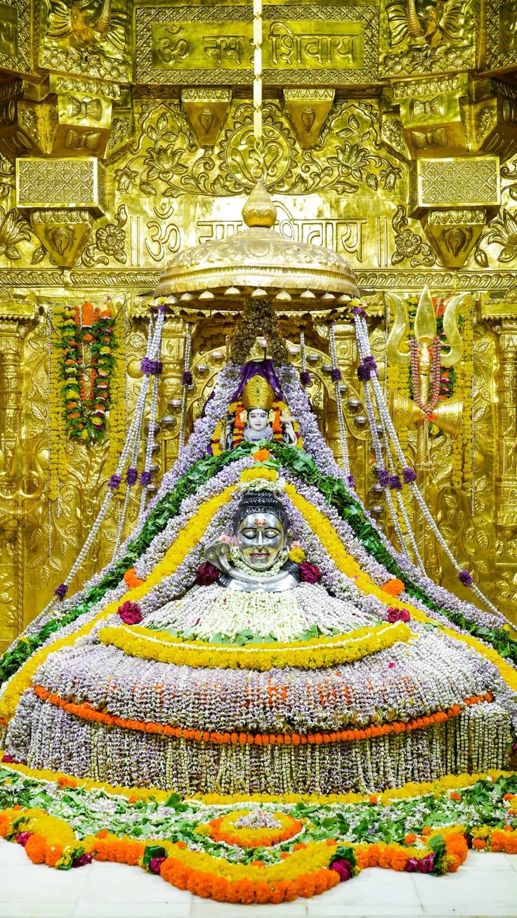 a large statue made out of flowers and other items in front of a golden wall