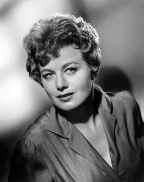 an old black and white photo of a woman with short hair smiling at the camera