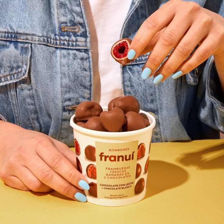 a woman with blue nails is holding a cup of ice cream and some chocolate candies