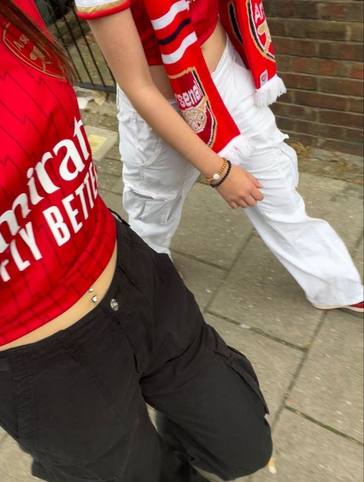 two people dressed in red and white are walking down the street with their hands on their hipss