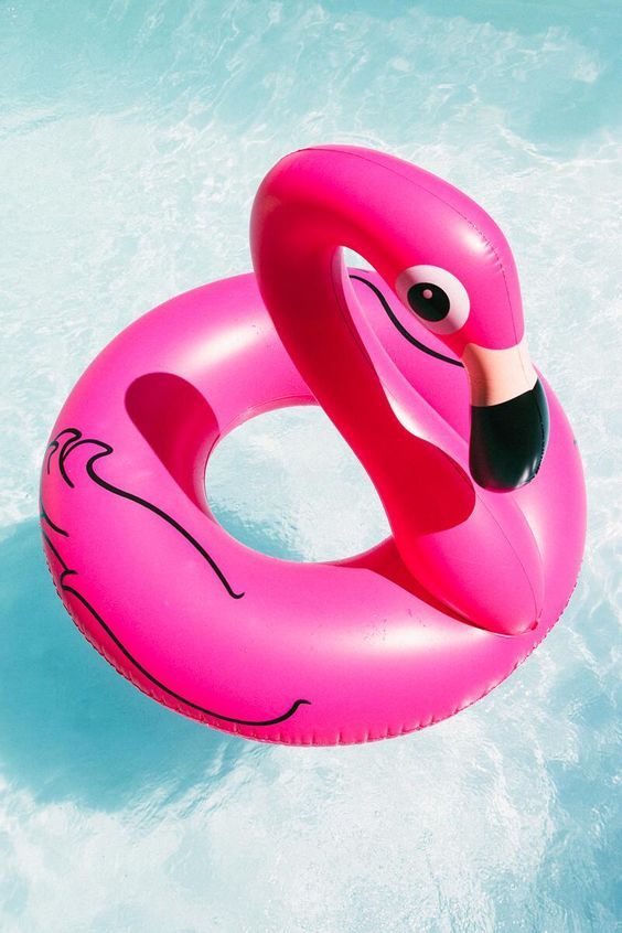 an inflatable pink flamingo float floating on the water with its head sticking out