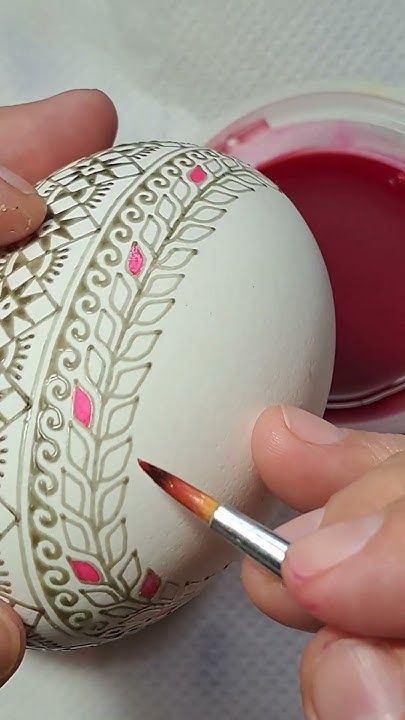 someone is painting an egg with red paint on the outside and pink flowers on the inside