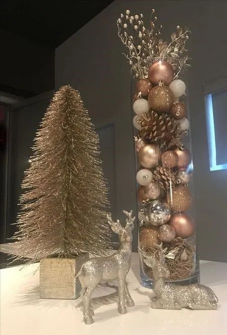 two glass vases filled with christmas ornaments and silver deer figurines sitting on a counter