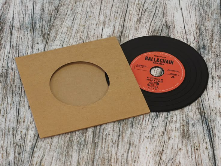 an old record sitting on top of a wooden table next to a brown cardboard box