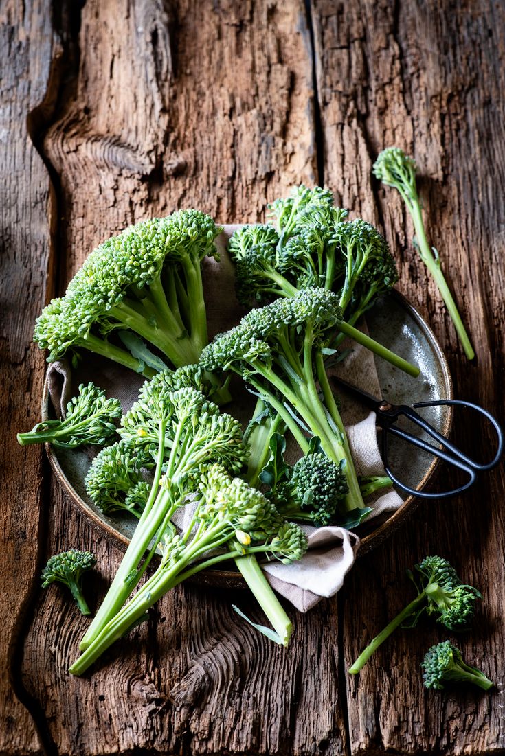 broccoli florets in a bowl with tongs on a wooden table