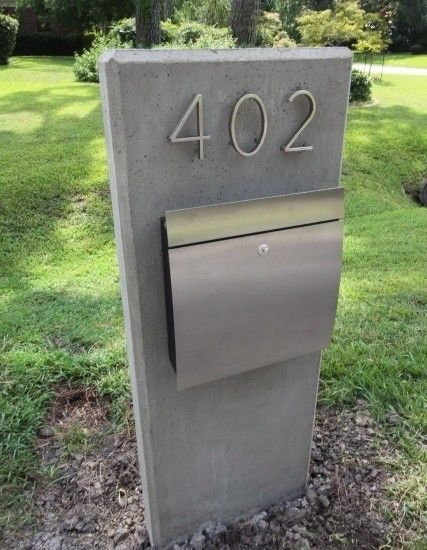 a mailbox sitting in the middle of a field with grass and trees behind it