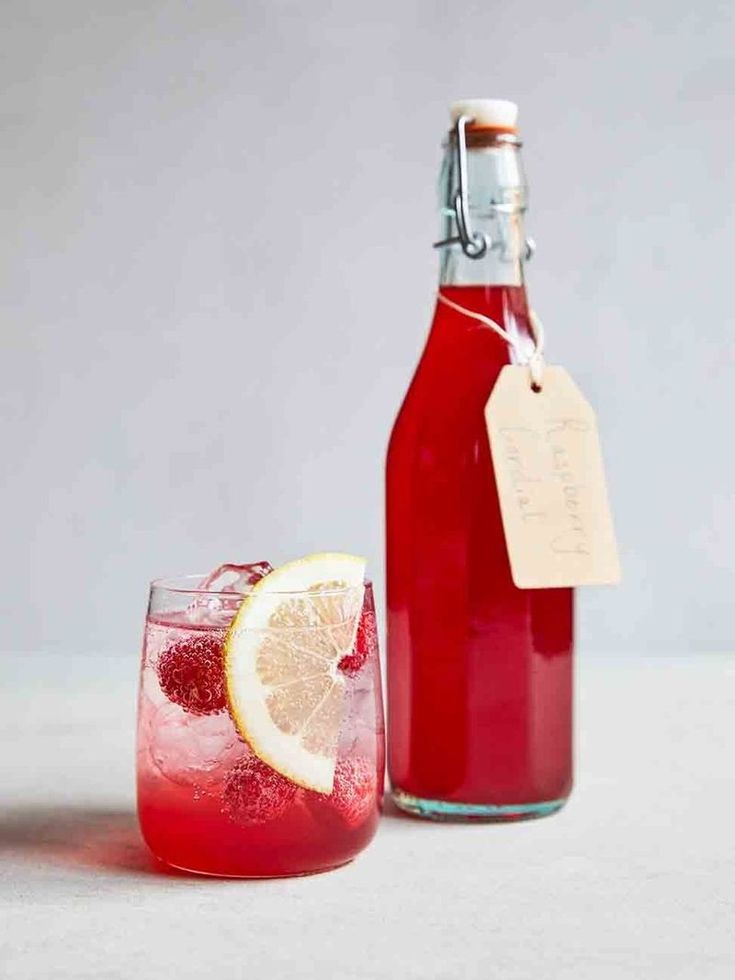 a bottle of wine next to a glass with a lemon slice on it and a label