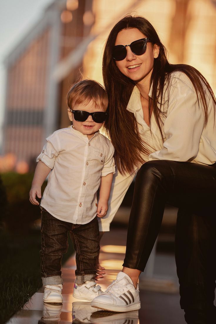 a woman kneeling down next to a little boy on a skateboard