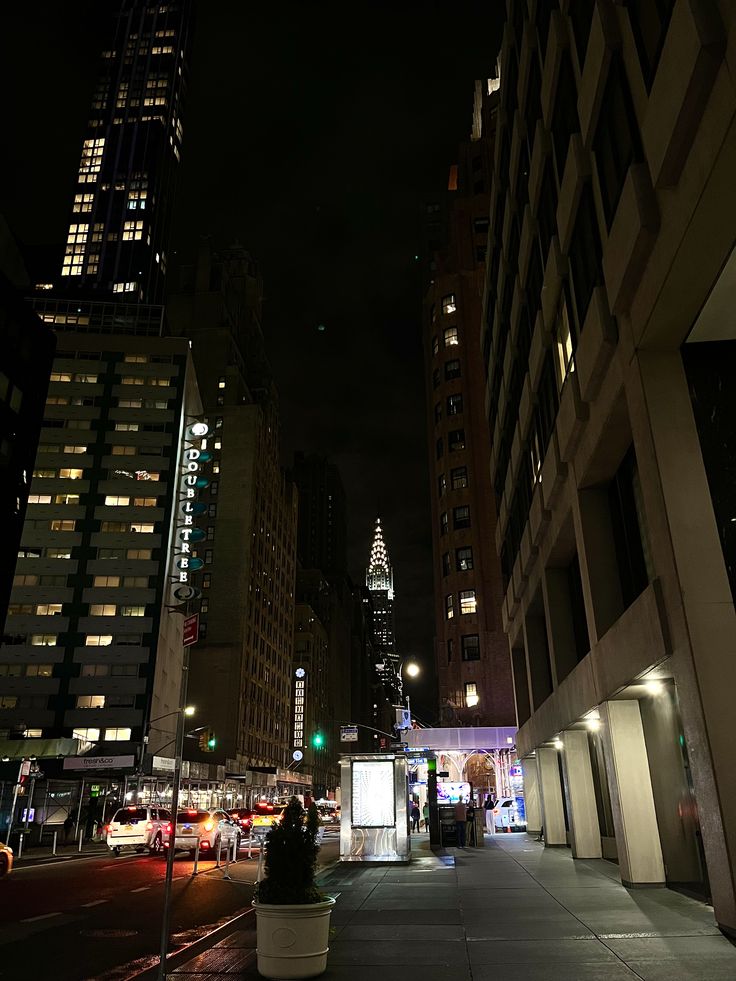 a city street at night with tall buildings