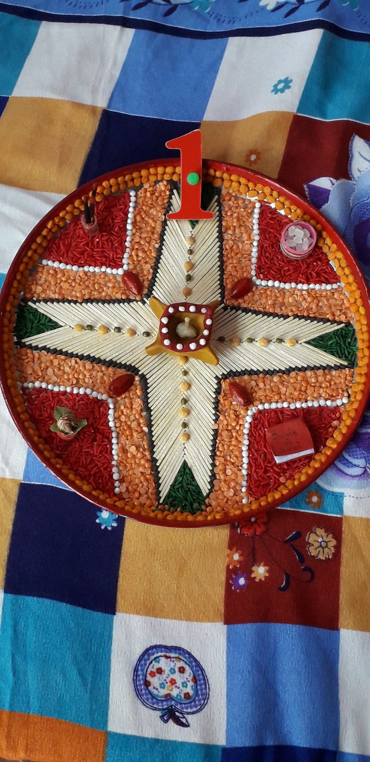 a decorative plate is sitting on a colorful tablecloth with flowers and other decorations around it