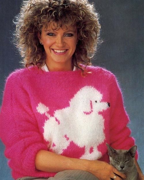 a woman in a pink sweater holding a cat