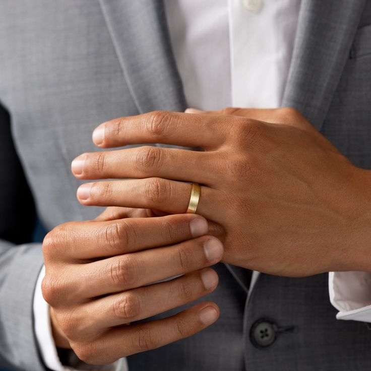 a man wearing a suit and holding his wedding ring in his left hand with both hands