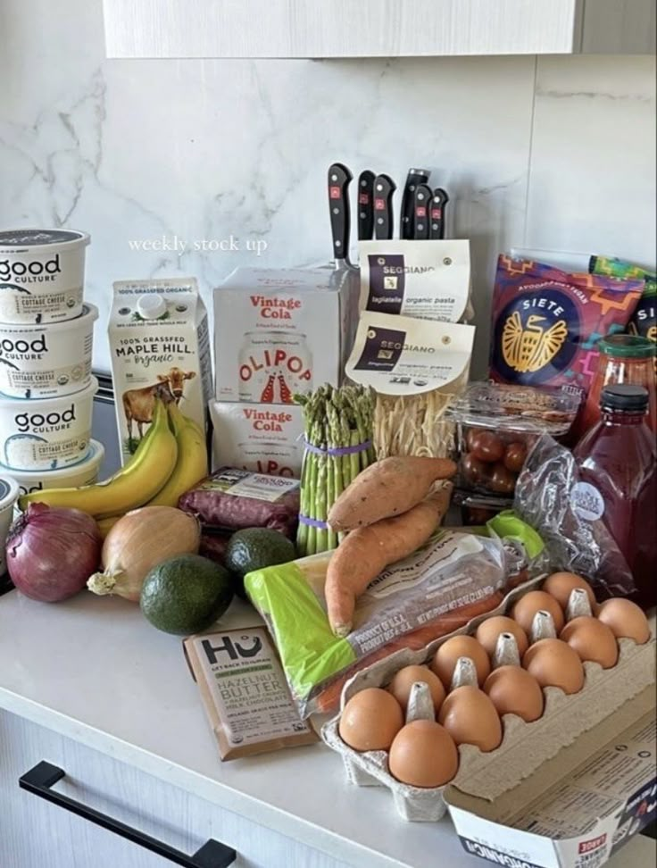 an assortment of food on a kitchen counter with eggs, avocado, and other items