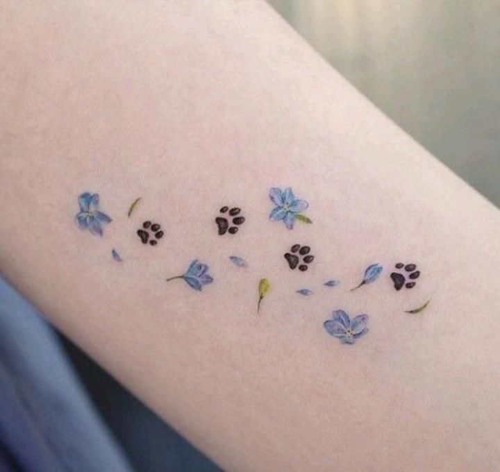 a woman's arm with small blue flowers and dog paw prints on the side