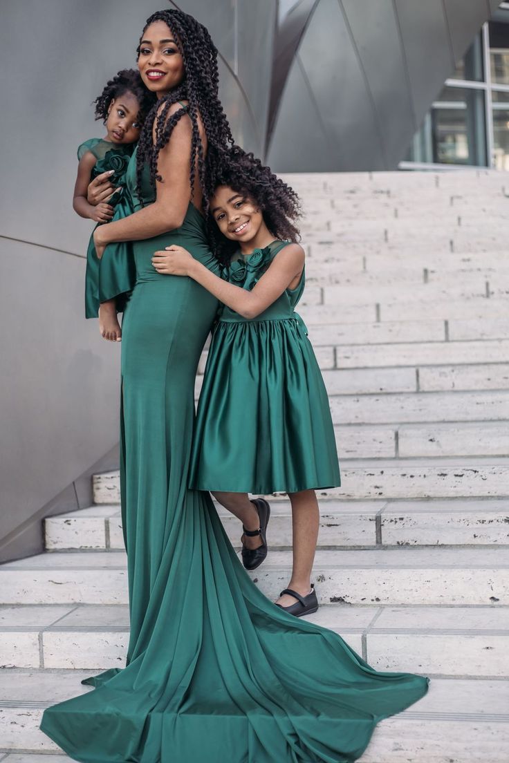 three women in green dresses standing on steps with their arms around each other and smiling at the camera