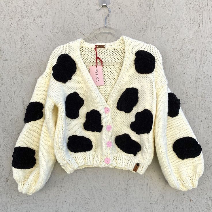 a sweater with black and white spots hanging on a hook in front of a wall