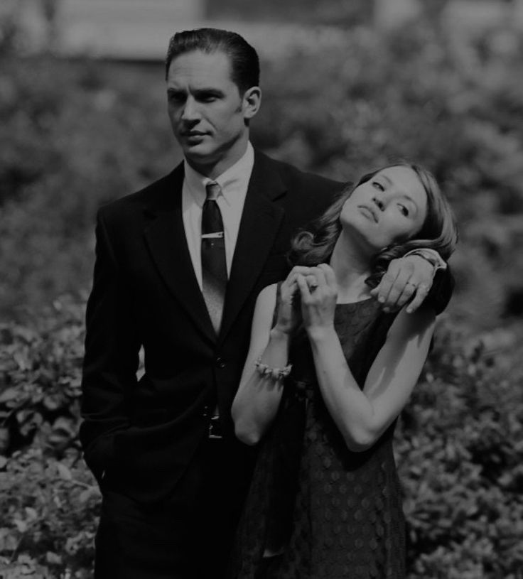 a man in a suit and tie standing next to a woman with her arms around her neck