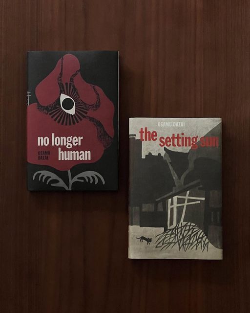 two books sitting next to each other on top of a wooden table with a black and red cover