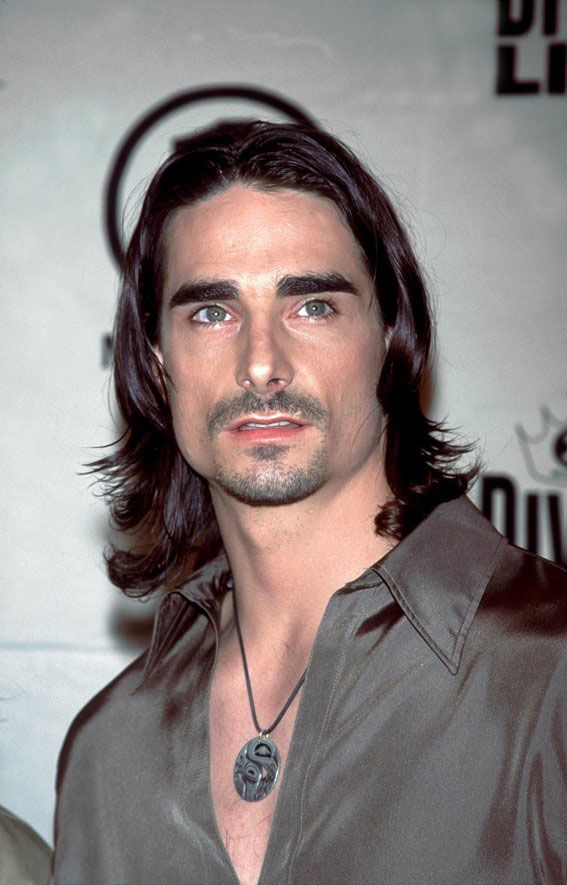 a man with long hair wearing a brown shirt