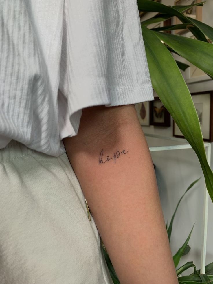 a woman's arm with the word love written in cursive writing on it