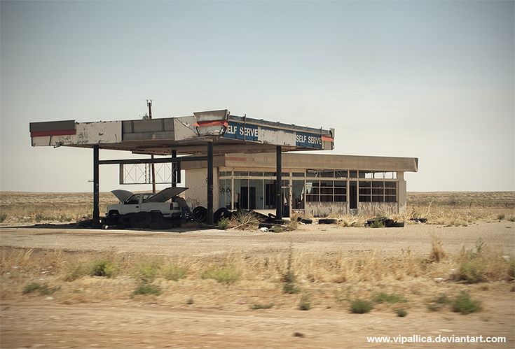 an old gas station in the middle of nowhere with no cars parked outside and there is only one car on the lot