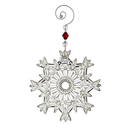 a snowflake ornament hanging from a metal hook on a white background