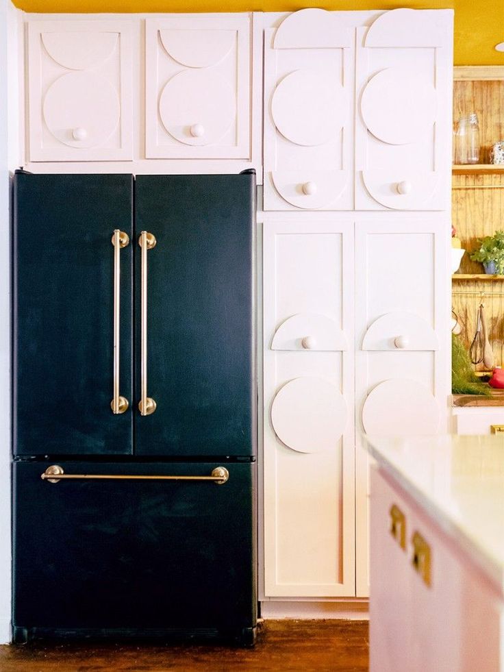 a black refrigerator freezer sitting inside of a kitchen next to white cupboards with gold handles