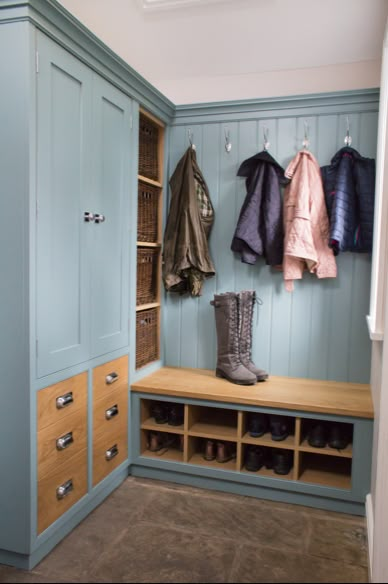 a blue closet with several coats and boots hanging on the wall next to it is an entry way