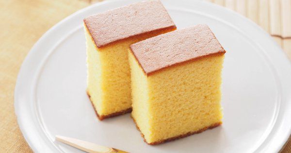 two pieces of yellow cake sitting on top of a white plate