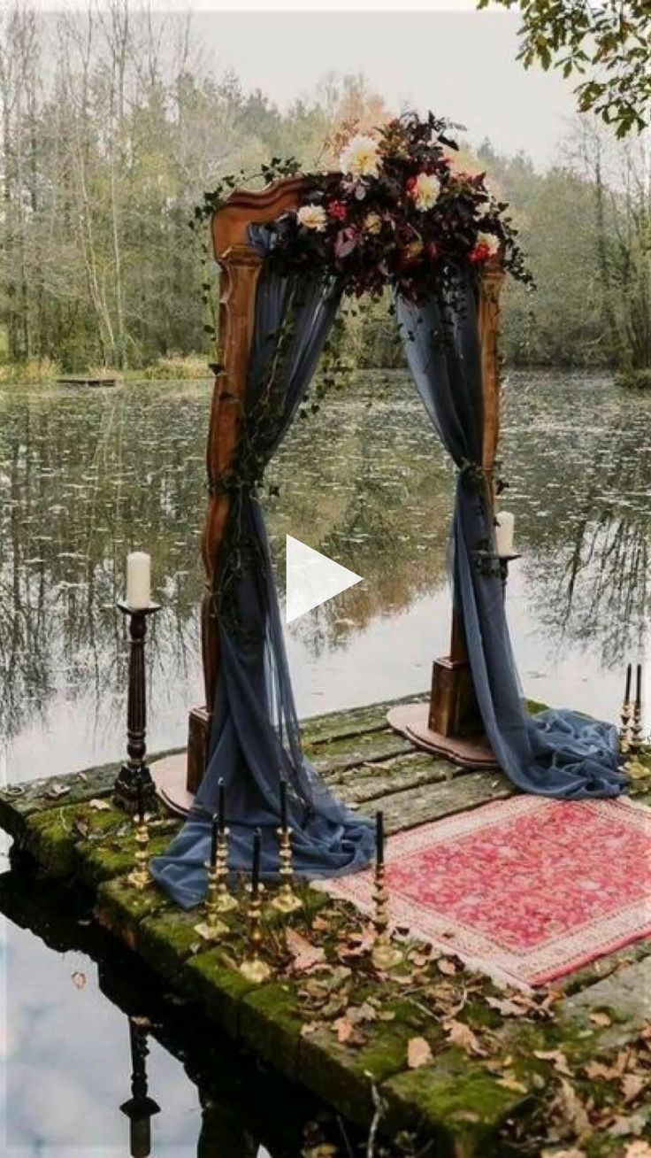 an outdoor ceremony setup with flowers and blue draping on the ground next to water