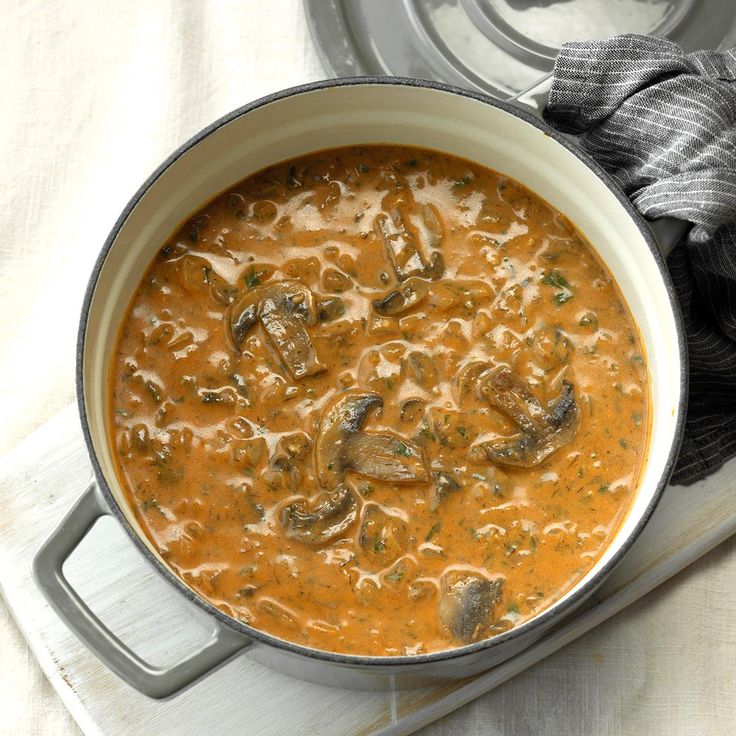 a pot filled with soup sitting on top of a white counter next to a pair of gloves